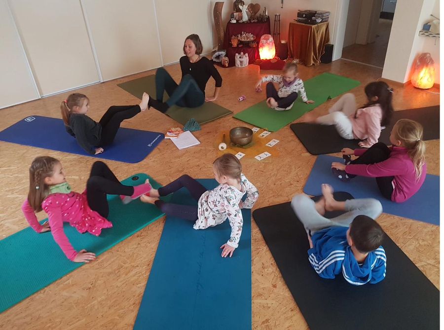 Kindergruppe beim Yoga-Fußspiel auf Matten